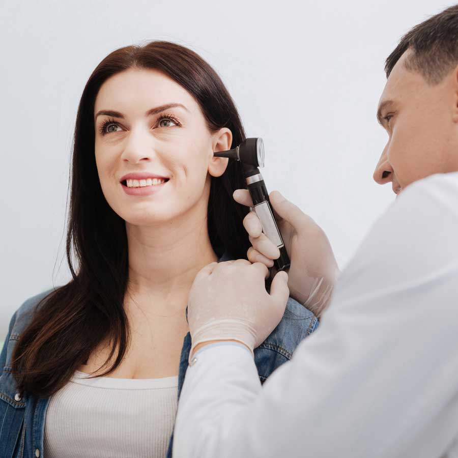 Hearing professional examining a woman's ear