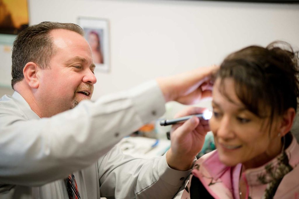 Hearing instrument specialist examining a woman's ear during a hearing test